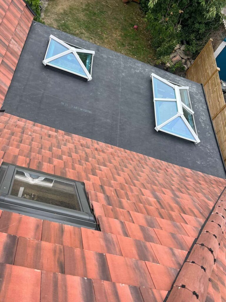 This is a photo taken from the roof ridge looking down a tiled pitched roof on to a flat roof. Works carried out by LJ Roofing Criklade